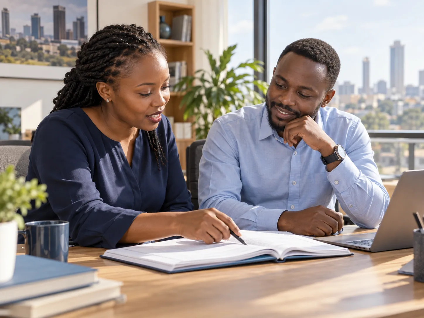 Two finance colleagues reviewing an open ledger together in a sunlit office